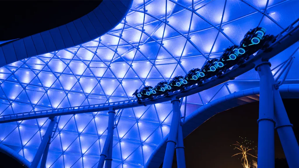 TRON lightcycles coast by at Magic Kingdom illuminated by blue canopy